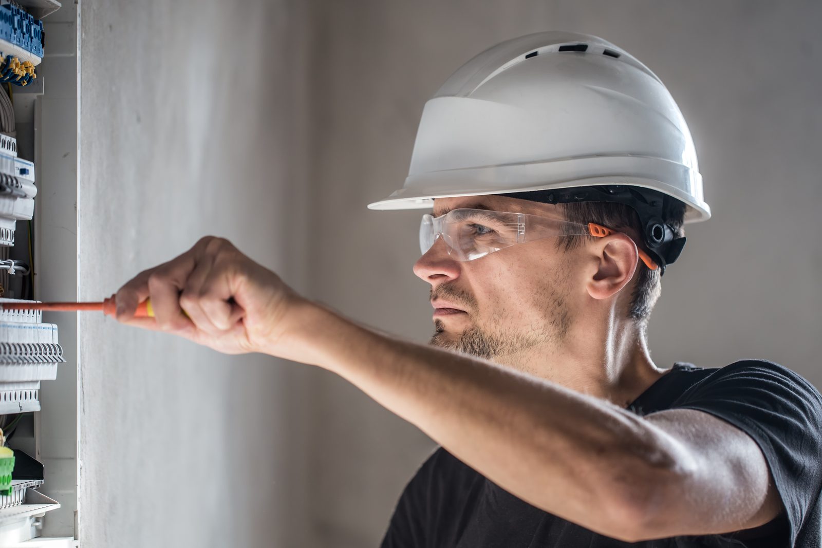 Eletricista trabalhando em um quadro de distribuição com disjuntores